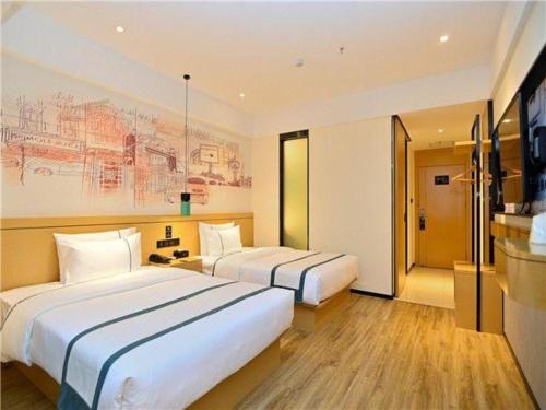 a hotel room with two beds and a painting on the wall at City Comfort Inn Kunming High Speed Railway South Station Yongxin Harvard in Kunming