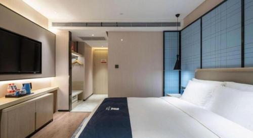 a bedroom with a large bed and a flat screen tv at Echarm Hotel Shenyang Zhongjie North Station Metro Station in Shenyang