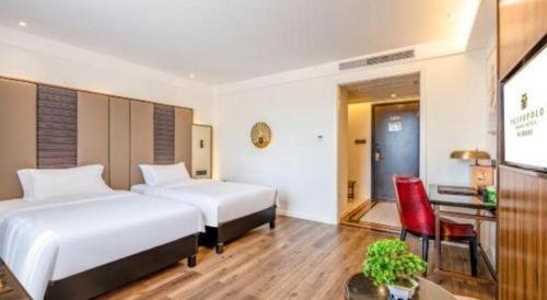 a hotel room with two beds and a red chair at Jinjiang Metropolo Haikou East High Speed Railway Station Normal University in Haikou