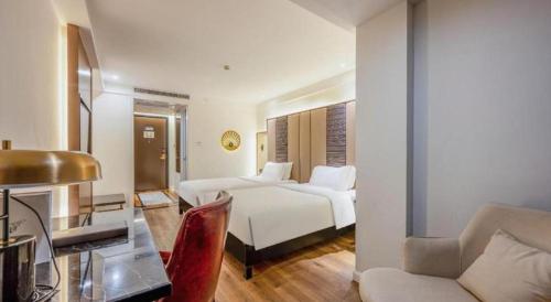 a hotel room with two beds and a desk and a couch at Jinjiang Metropolo Haikou East High Speed Railway Station Normal University in Haikou