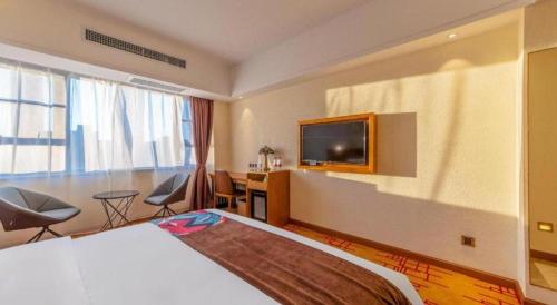 a hotel room with a bed and a flat screen tv at James Joyce Coffetel Kunming Railway Station Huancheng Nan Road Metro Station in Kunming