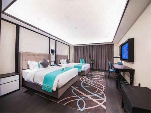 a room with two beds and a desk and a television at Xana Hotelle Jinan Wuanfu Interchange Huafu International Square in Jinan
