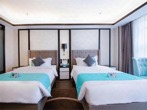 a hotel room with two beds with blue and white sheets at Xana Hotelle Jinan Wuanfu Interchange Huafu International Square in Jinan