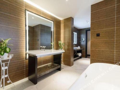 a bathroom with a sink and a large mirror at Xana Hotelle Jinan Wuanfu Interchange Huafu International Square in Jinan