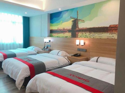 a room with four beds and a painting of a windmill at Jun Hotel Guangdong Zhanjiang Xiashan South Railway Station in Zhanjiang