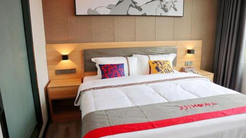 a bedroom with a large bed with pillows at Jun Hotel Guangdong Zhanjiang Xiashan South Railway Station in Zhanjiang