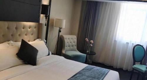 a bedroom with a bed and a chair and a window at Xana Hotelle Wuxi Railway Station Zhongshan Road in Wuxi