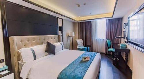a hotel room with a large bed and a desk at Xana Hotelle Wuxi Railway Station Zhongshan Road in Wuxi