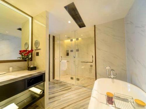 un baño con bañera y ducha de cristal en Dahe Jinjiang Hotel, en Zhengzhou