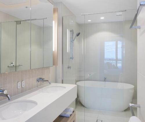 a white bathroom with two sinks and a tub at Queen's Wharf Residences Official in Brisbane