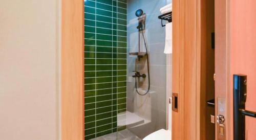 a green tiled shower in a bathroom with a toilet at GreenTree Inn Express Lanzhou West Passenger Station Lanzhou Center in Lanzhou