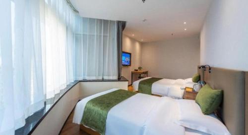 a hotel room with two beds and a television at GreenTree Inn Express Lanzhou West Passenger Station Lanzhou Center in Lanzhou