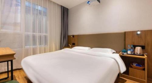 a large white bed in a hotel room at GreenTree Inn Express Lanzhou West Passenger Station Lanzhou Center in Lanzhou