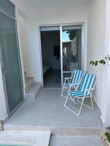 two blue chairs sitting on a patio next to a house at Casa Ha Hermosa Casa en Progreso Yucatan in Progreso