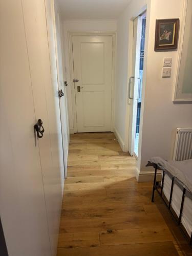 a hallway with a white door and a wooden floor at East Dulwich - double room with en suite in London