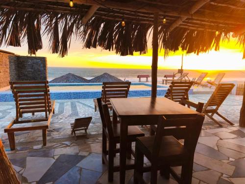 a wooden table and chairs under a straw umbrella at Cabañas en Playas Villamil, Bungalows! in Playas