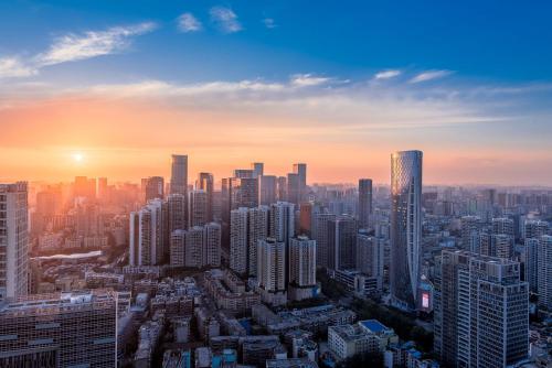 a city skyline with the sun setting in the sky at 云享城居 SKY高空Loft公寓酒店 春熙路九眼桥店 in Chengdu