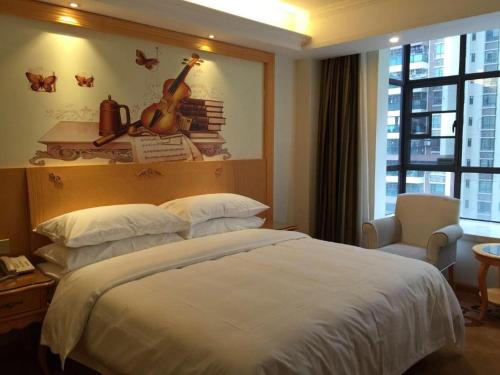 a bedroom with a bed and a guitar on the wall at Vienna Hotel Guangdong Zhaoqing Sihui Tianguangxu in Zhaoqing