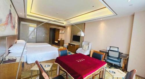 a hotel room with a bed and a desk and chairs at Venus Royal Hotel Nanning East High-Speed Railway Station in Nanning