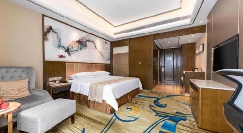 a bedroom with a bed and a couch and a tv at Venus Royal Hotel Nanning East High-Speed Railway Station in Nanning
