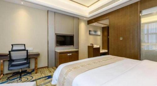 a bedroom with a bed and a desk and a chair at Venus Royal Hotel Nanning East High-Speed Railway Station in Nanning