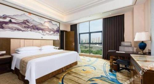 a bedroom with a large bed and a desk and a large window at Venus Royal Hotel Nanning East High-Speed Railway Station in Nanning