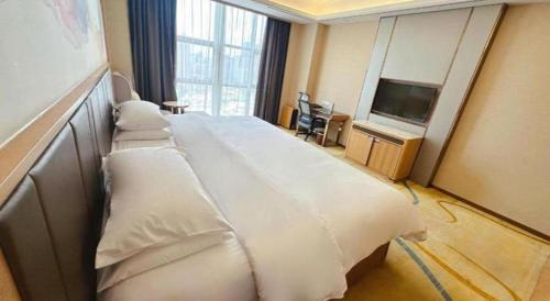 a hotel room with a large bed and a flat screen tv at Venus Royal Hotel Nanning East High-Speed Railway Station in Nanning
