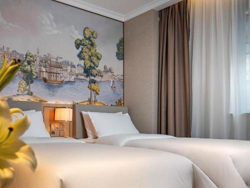 a hotel room with two beds and a painting on the wall at Vienna Hotel Hangzhou East Railway Station West Square in Hangzhou