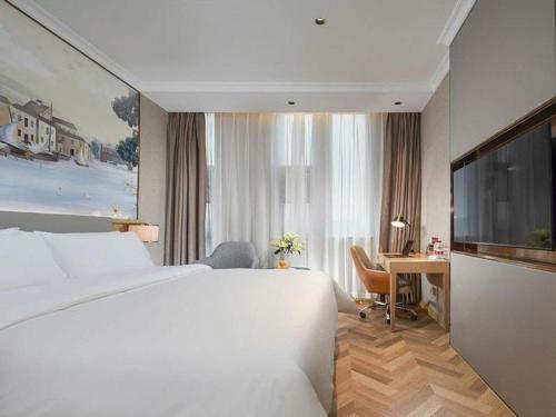 a hotel room with a large bed and a desk at Vienna Hotel Hangzhou East Railway Station West Square in Hangzhou