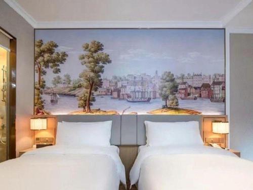 two beds in a room with a painting on the wall at Vienna Hotel Hangzhou East Railway Station West Square in Hangzhou