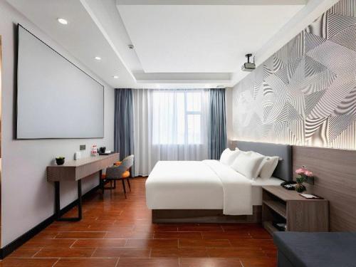 a hotel room with a bed and a desk and a projection screen at Borrman Hotel Huizhou Danshui High-speed Railway Huiyang Station in Huizhou