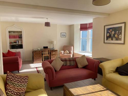 a living room with a red couch and chairs at Sant Seiriol in Beaumaris