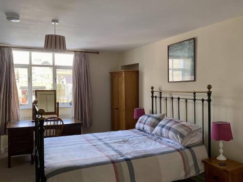 a bedroom with a bed and a desk and a window at Sant Seiriol in Beaumaris