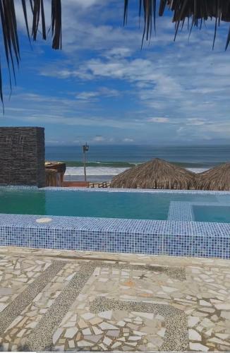 a swimming pool with a view of the ocean at Cabañas en Playas Villamil, Bungalows! in Playas