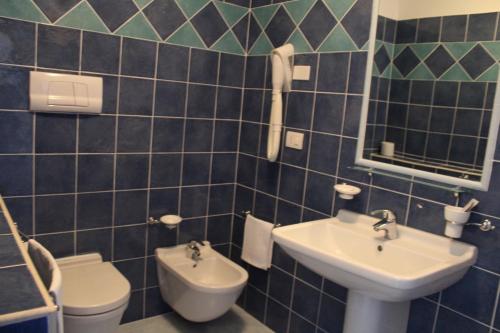 bagno con lavandino, servizi igienici e specchio di Hotel Resort Poggio degli Ulivi a Rodi Garganico