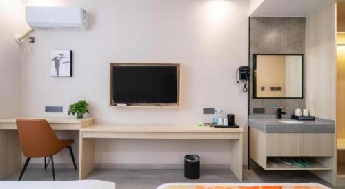a room with a desk with a television and a sink at Shell Hotel Wuxi Huishan District Chang'an Town in Wuxi