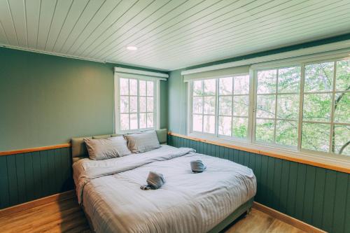a bed in a room with green walls and windows at Khaoyai Art Tree in Pong Talong