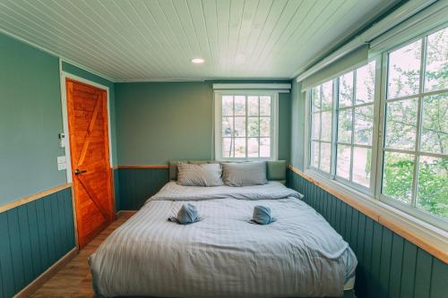 two beds in a room with two windows at Khaoyai Art Tree in Pong Talong