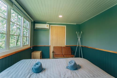 a bedroom with blue walls and a bed with two hats on it at Khaoyai Art Tree in Pong Talong
