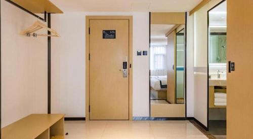 a hallway with a door and a room with a bed at City Comfort Inn Kunming Dashuying Yejin Hospital Wangdaqiao in Kunming