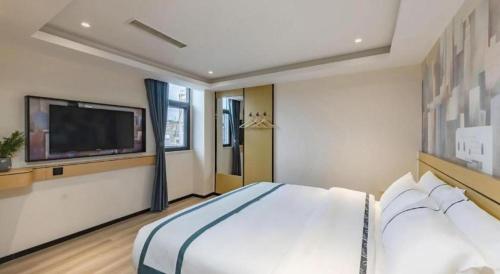a bedroom with a large bed and a flat screen tv at City Comfort Inn Kunming Dashuying Yejin Hospital Wangdaqiao in Kunming