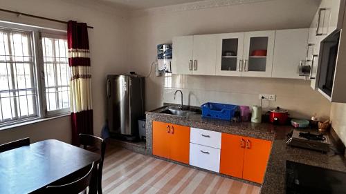 a kitchen with orange and white cabinets and a table at Raniban Suites - Apartment Home in Kathmandu