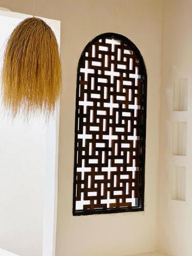 a black and white painting on a wall next to a window at Tulia House Lamu in Lamu