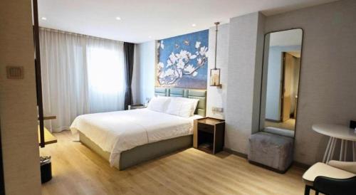 a hotel room with a bed and a mirror at Magnotel Hotel Suzhou Shiquan Street Wangshiyuan in Suzhou