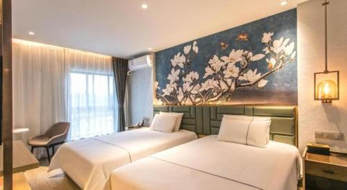 two beds in a hotel room with a painting on the wall at Magnotel Hotel Suzhou Shiquan Street Wangshiyuan in Suzhou