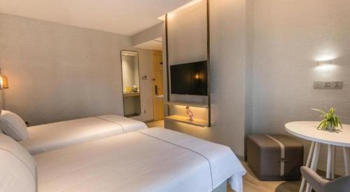 a hotel room with two beds and a television at Magnotel Hotel Suzhou Shiquan Street Wangshiyuan in Suzhou