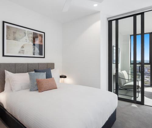 a bedroom with a white bed and a sliding glass door at Queen's Wharf Residences Official in Brisbane