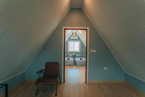 a room with an attic with a chair and a window at Khaoyai Art Tree in Pong Talong