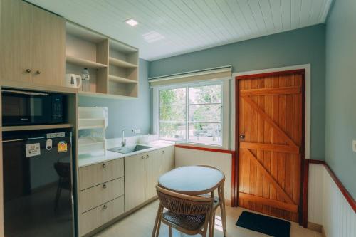 a kitchen with a door and a table and a stool at Khaoyai Art Tree in Pong Talong