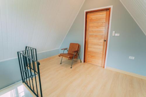 a staircase with a chair and a wooden door at Khaoyai Art Tree in Pong Talong